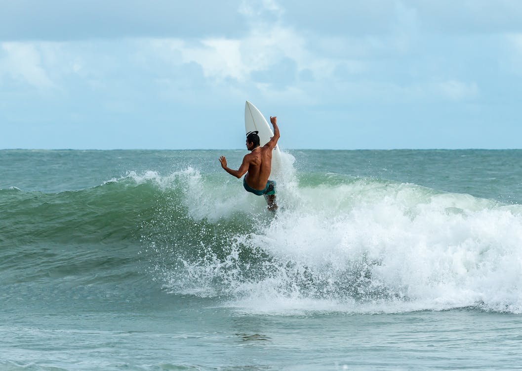 Surfista executando manobra em onda potente com spray de água